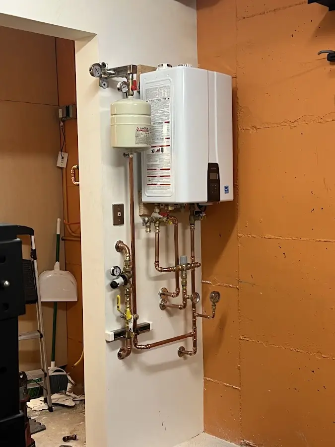 Plumbing technician inspecting water heater connections in Dexter